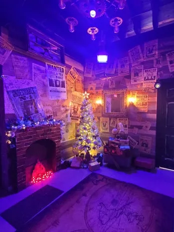 Decorated event room with Christmas tree, fireplace, and themed wanted-poster walls under purple lighting