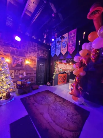Event space with house banners, balloon arch, and purple stage lighting