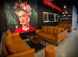 Lounge area with tan leather sofas and large Frida Kahlo portrait mural